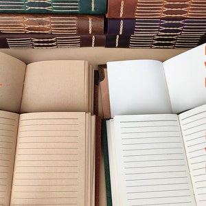 May include: Four leather-bound journals with different paper options: blank kraft paper, lined kraft paper, blank white paper, and lined white paper.