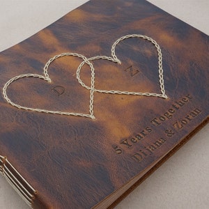 May include: A brown leather photo album with two stitched hearts and the text "5 Years Together Diliana & Zoran".