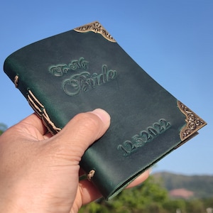 May include: A dark green leather journal with gold accents and the text "To My Bride" and "12.5.2022" embossed on the cover.
