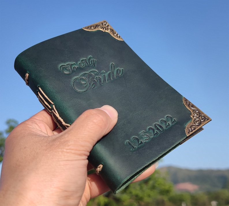 May include: A dark green leather journal with gold accents and the text "To My Bride" and "12.5.2022" embossed on the cover.