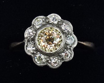 May include: A silver ring with a round, yellow-brown gemstone surrounded by smaller, clear gemstones in a flower-shaped setting.