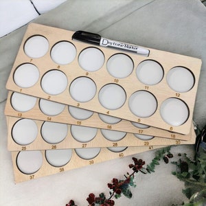 May include: A wooden organizer with 41 numbered circular compartments, ideal for storing small items. The organizer is made of light wood and has a dry erase marker on top.