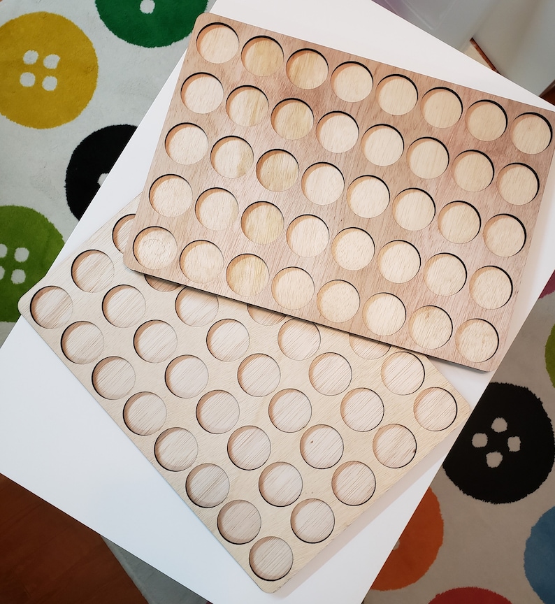 May include: Two wooden trays with circular cutouts for holding small items. The trays are made of light brown wood and have a natural finish.