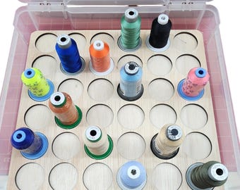 May include: A wooden thread organiser with 36 circular slots for storing spools of thread. The organiser is filled with various colours of thread, including green, blue, orange, and pink.
