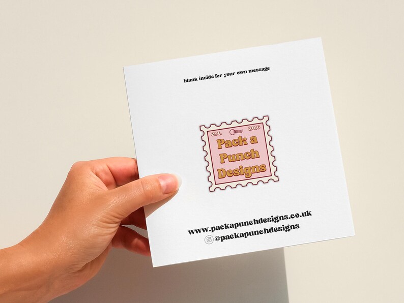 A hand holding a white card with text and an image of a stamp.