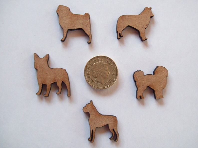 May include: Five wooden dog silhouette cutouts in various breeds. The cutouts are brown and are approximately the size of a UK one pound coin.