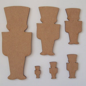 May include: Set of six wooden nutcracker ornaments in various sizes. The ornaments are all in the shape of a traditional nutcracker, with a hat, moustache, and a long coat. The ornaments are made of unfinished wood and are ready to be painted or decorated.