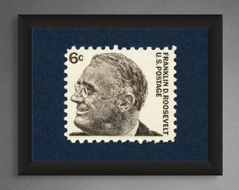 Könnte beinhalten: Eine gerahmte Schwarzweiß-Briefmarke mit einem Porträt von Franklin D. Roosevelt und dem Text "FRANKLIN D. ROOSEVELT U.S. POSTAGE 6c" auf der Marke.