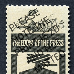 May include: A vintage postage stamp with a black and white illustration of a hand holding a quill pen. The stamp has the text "Freedom of the Press" printed in white on a black background.