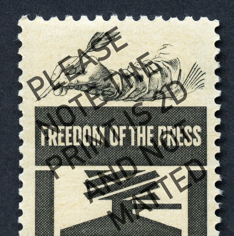 May include: A vintage postage stamp with a black and white illustration of a hand holding a quill pen. The stamp has the text "Freedom of the Press" printed in white on a black background.