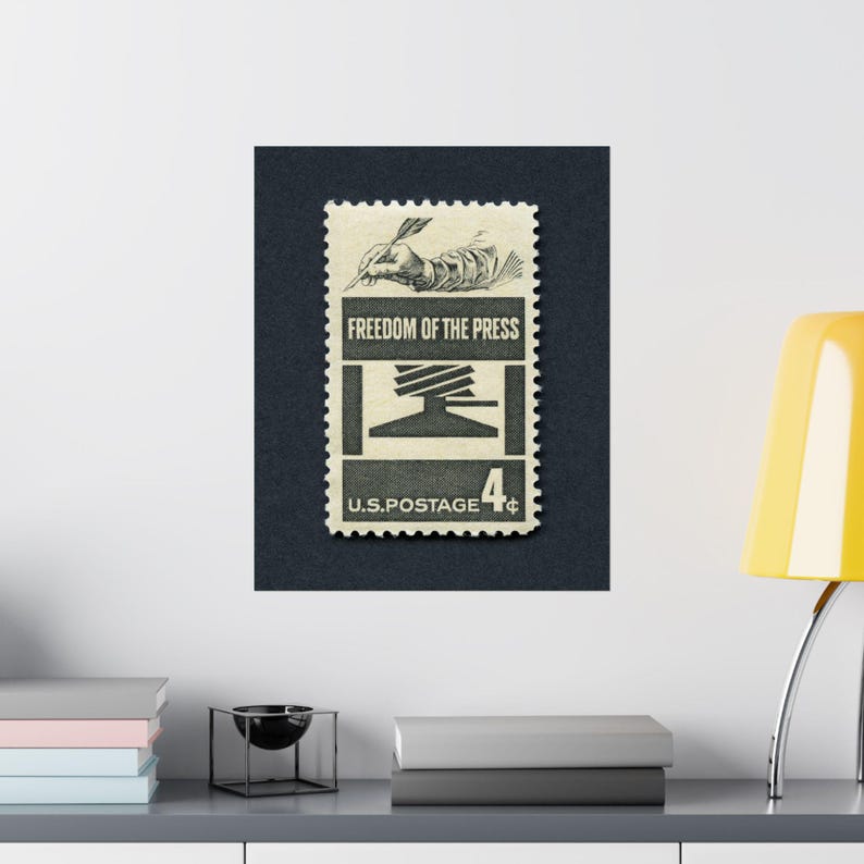 May include: A vintage US postage stamp with a black and white illustration of a hand holding a quill pen and a printing press. The stamp reads "Freedom of the Press" and "U.S. Postage 4&cent;".