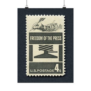 May include: A vintage US postage stamp with a 4-cent denomination. The stamp features a black and white illustration of a hand holding a quill pen, writing on a printing press. The text "FREEDOM OF THE PRESS" is printed in black on a white background.
