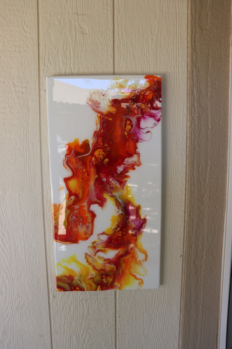 May include: Abstract painting on canvas with swirling red, orange, and yellow paint on a white background.