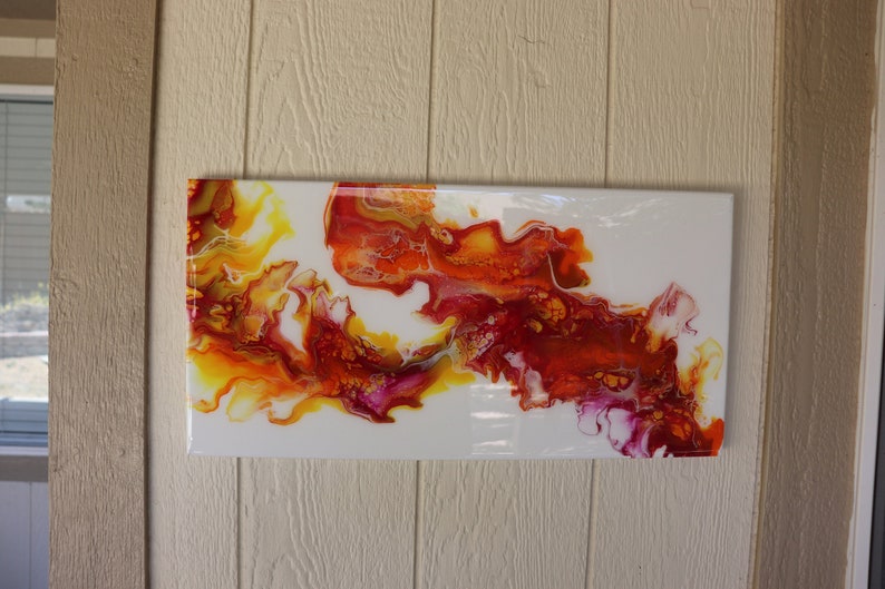May include: Abstract painting with swirling red, orange, and yellow paint on a white background.