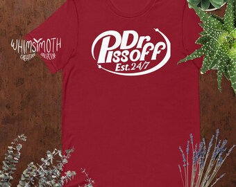 Puede incluir: Camiseta roja con un gráfico blanco de un logotipo que dice "Dr. Pissoff" y "Est. 24/7".