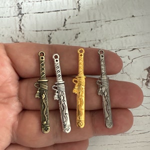 May include: Four silver and gold charms shaped like swords with a dragon design. The charms have a loop at the top for attaching to a necklace or bracelet.