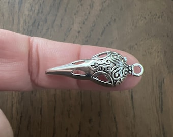 May include: Silver pendant in the shape of a bird's head with intricate details and a loop for attaching a chain.