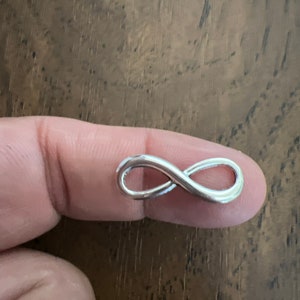 May include: A silver infinity symbol charm, a popular choice for jewelry making.