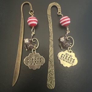 May include: Two bronze bookmark charms with a monkey, a red and white striped bead, and a tag that says "Not my circus, not my monkeys".