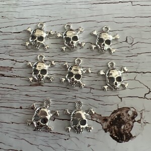 K&ouml;nnte beinhalten: Zehn silberne Totenkopf- und Knochen-Anh&auml;nger. Die Anh&auml;nger sind detailliert und haben einen Vintage-Look.