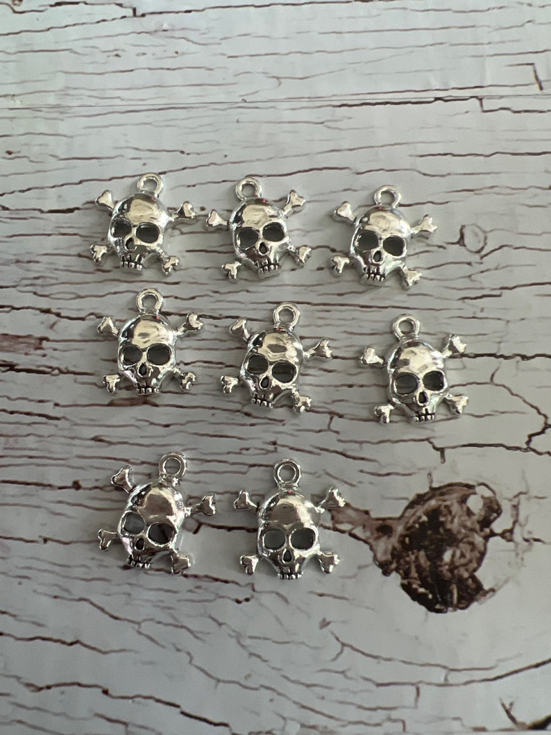 K&ouml;nnte beinhalten: Zehn silberne Totenkopf- und Knochen-Anh&auml;nger. Die Anh&auml;nger sind detailliert und haben einen Vintage-Look.
