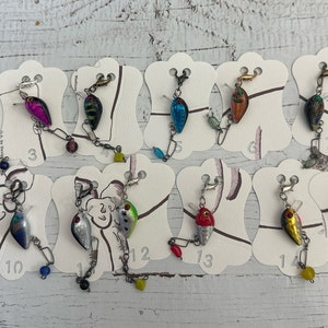 May include: A set of 16 fishing lure earrings, each with a different color and design. The earrings are displayed on white cards with numbers 1 through 16.