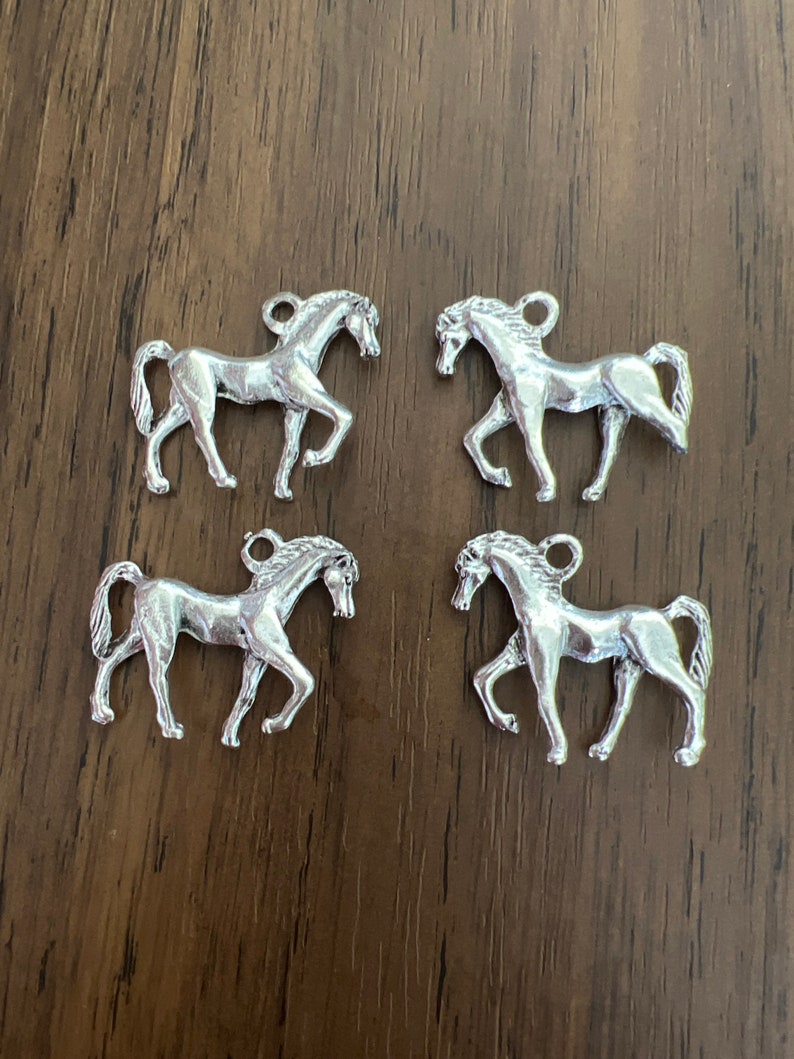 May include: Four silver horse charms, each with a detailed design, perfect for adding a touch of equestrian elegance to jewelry or crafts.