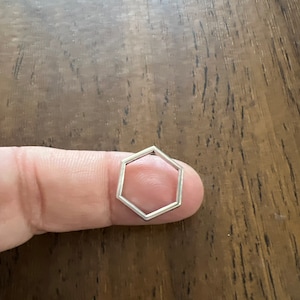 May include: A silver hexagonal ring with a simple, open design.