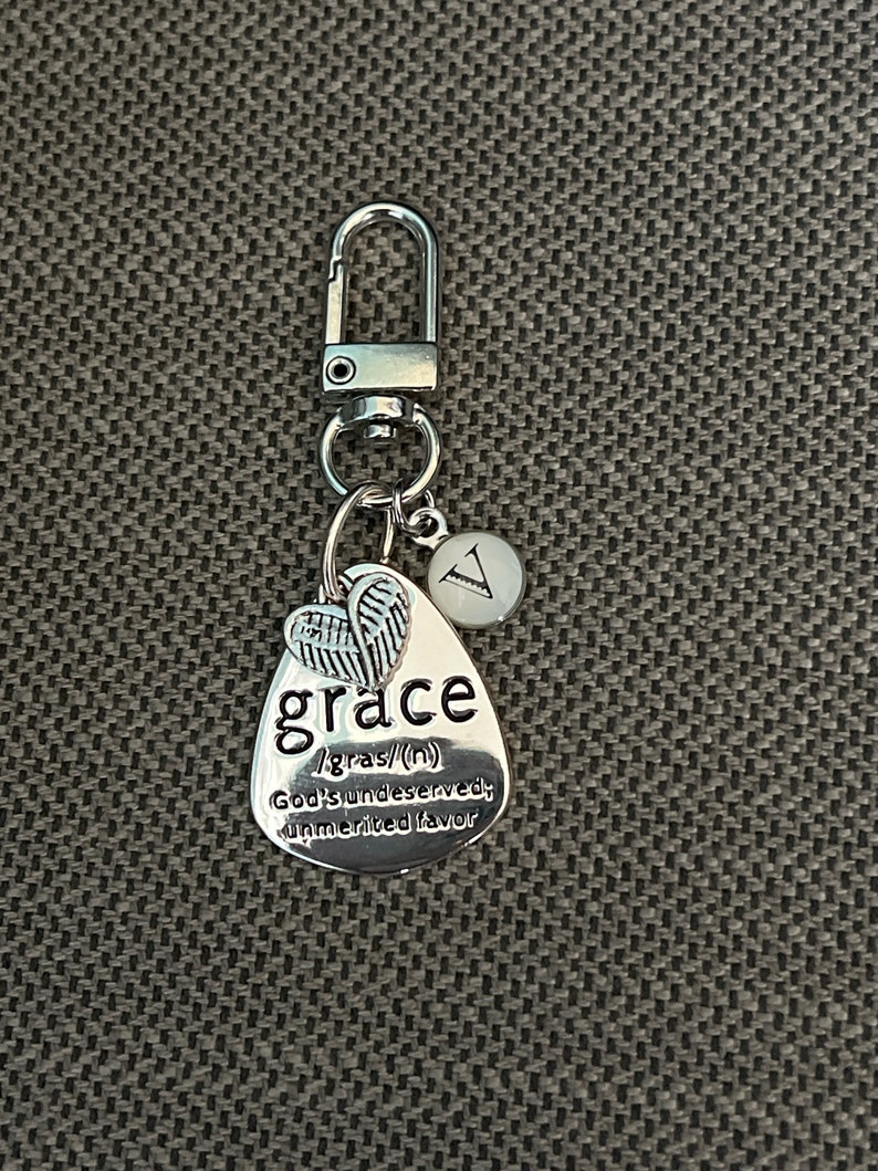 May include: Silver keychain with a charm that says "grace" and defines it as "God's undeserved, unmerited favor". The charm also has a small pair of angel wings.