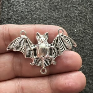 May include: Silver-toned metal bat charm with detailed wings and a hanging loop.