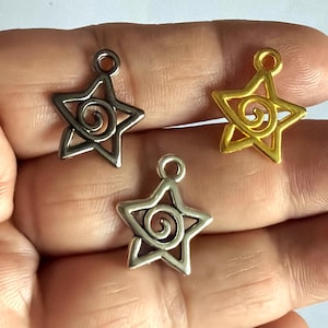 May include: Three star-shaped metal charms, each featuring a central spiral design and a small loop at the top for attachment. The charms are finished in three distinct metallic colors: a dark gunmetal grey, a bright gold, and a polished silver.