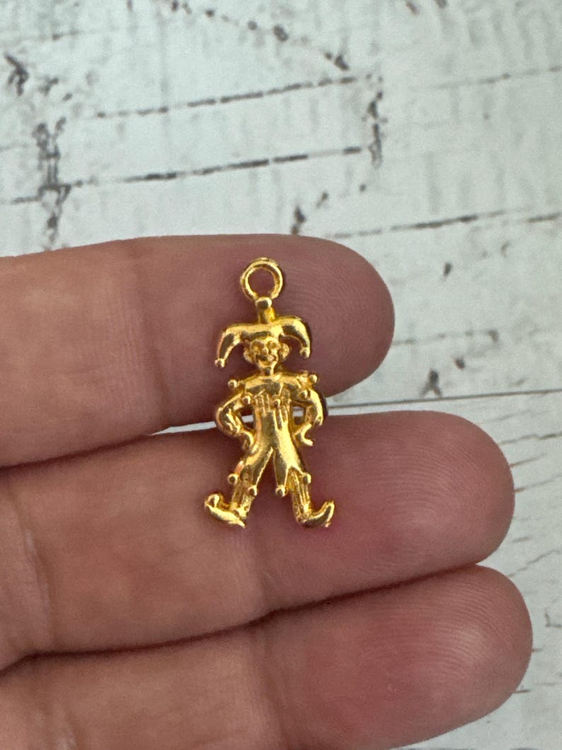K&ouml;nnte beinhalten: Goldfarbener Metall-Anh&auml;nger mit einer Jester-Figur mit spitzen Hut, Gl&ouml;ckchen und einem skurrilen Ausdruck.