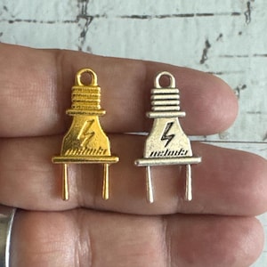 May include: Two metal electrical plug charms, one gold and one silver. Both charms feature a lightning bolt design.