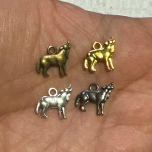 May include: Four wolf charms in two different finishes: gold and silver. The wolf charms are howling and have a detailed design.