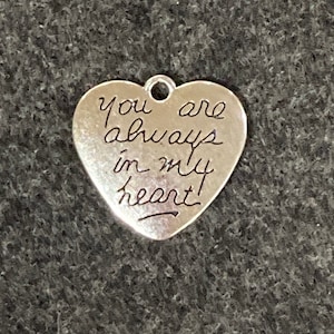 May include: Silver heart-shaped charm with the inscription "You are always in my heart!"