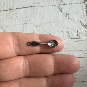 May include: A silver spoon charm with a loop for attaching to a necklace or bracelet.