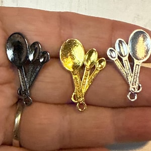 May include: Three sets of miniature metal spoons in silver, gold, and black. Each set includes four spoons of varying sizes.