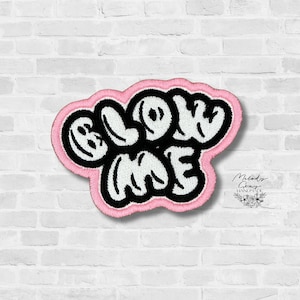 May include: Embroidered patch with the words "GLOW ME" in black bubble letters, outlined in white, on a pink cloud-shaped background. The patch is against a white brick wall.