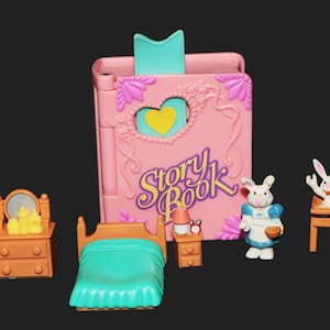 May include: A pink plastic storybook playset featuring a heart cutout, a teal bookmark, and the text Story Book. Includes a brown dresser with a mirror, a teal bed, a small nightstand with a lamp and clock, a rabbit figure, and a high chair.