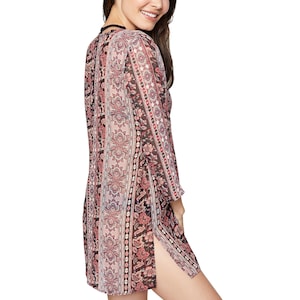 May include: A long-sleeved, sheer, pink and black patterned tunic with a side slit. The tunic has a paisley design.