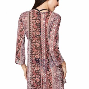 May include: A sheer, long-sleeved, floral print dress with a V-neckline. The dress has a paisley pattern with pink, red, and black colors.