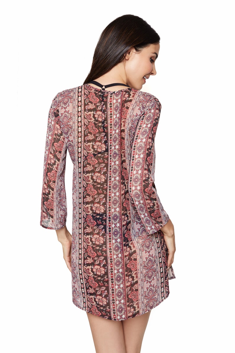 May include: A sheer, long-sleeved, floral print dress with a V-neckline. The dress has a paisley pattern with pink, red, and black colors.