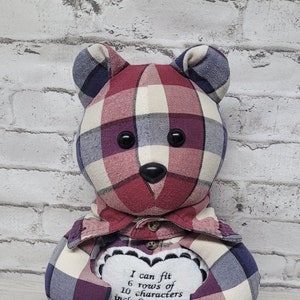 May include: A handmade teddy bear made from plaid fabric in burgundy, cream, and navy blue. The bear has black button eyes and a heart-shaped patch on its chest with text. The bear's left and right paws are labeled.