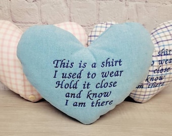 May include: Three heart-shaped pillows, one light blue, one pink and white gingham, and one blue and white gingham. The light blue pillow has the text "This is a shirt I used to wear Hold it close and know I am there" embroidered on it.