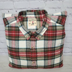 May include: A red, white, and green plaid flannel shirt with a Red Head Brand Co. label. The label has a red duck logo and the text "Since 1911".