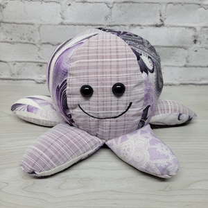 May include: A purple and white patchwork octopus plush toy with black button eyes and a stitched-on smile.