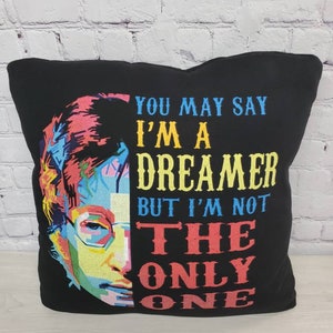 May include: Black pillow with a colorful pop art image of John Lennon and the text "You may say I'm a dreamer but I'm not the only one."