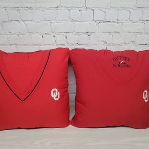 May include: Two red throw pillows with white embroidered logos. One pillow has the text "CUTTER & BUCK" and the other has a stylized "OU" logo.