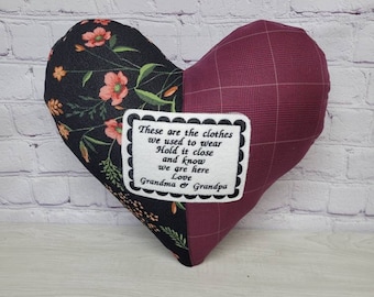 May include: A heart-shaped pillow with a floral print on one side and a burgundy plaid on the other. The pillow has a small embroidered patch with the text "These are the clothes we used to wear Hold it close and know we are here Love Grandma & Grandpa".