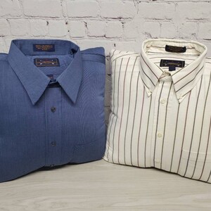 May include: Two decorative pillows shaped like shirts. One pillow is a solid blue with a white button and a pocket. The other pillow is white with thin red and white stripes and a white button.